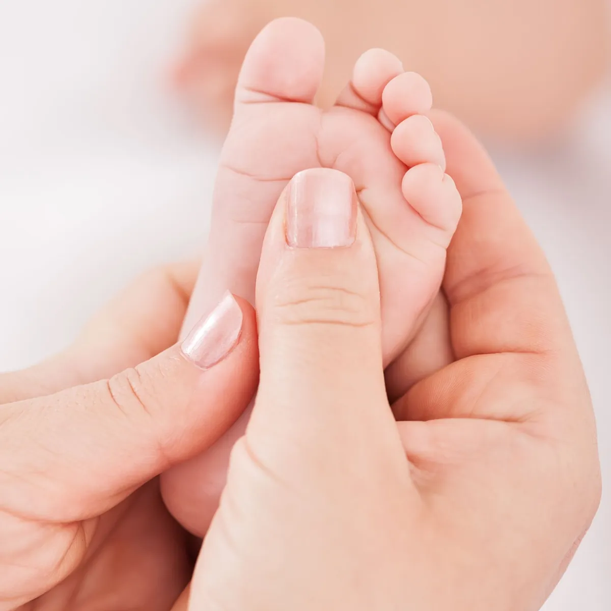 Zwei Hände umfassen sanft den Fuß eines Babys