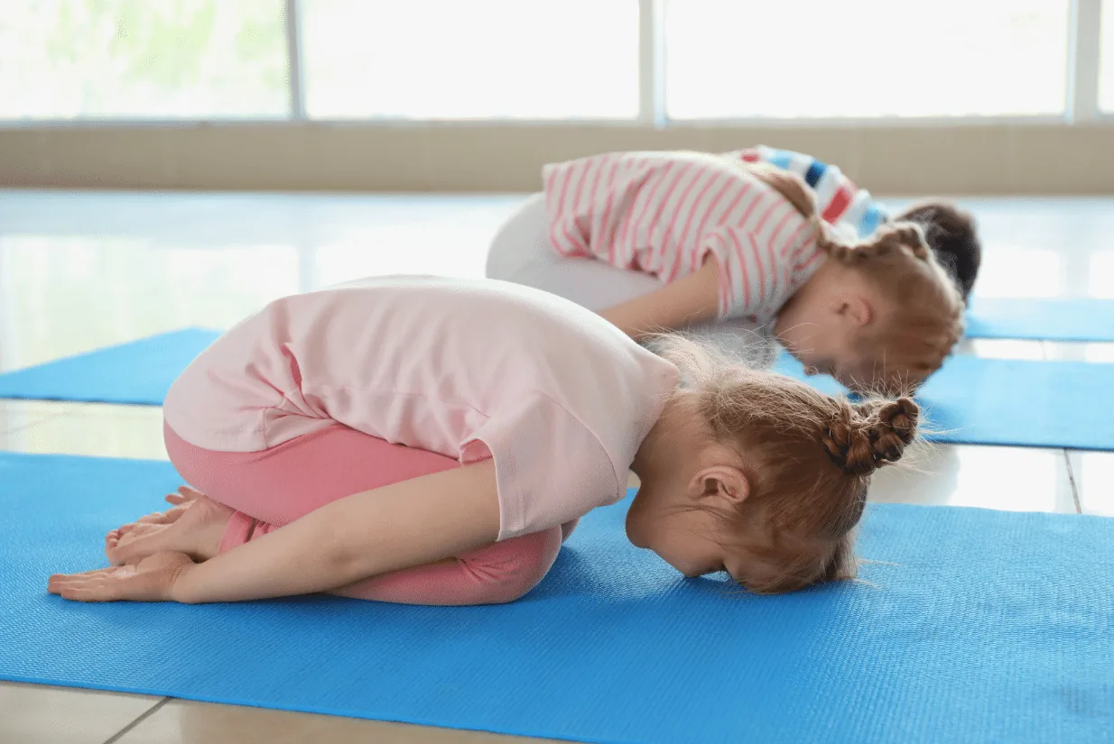 Zwei Kinder ruhen in der Haltung des Kindes auf ihren Yogamatten